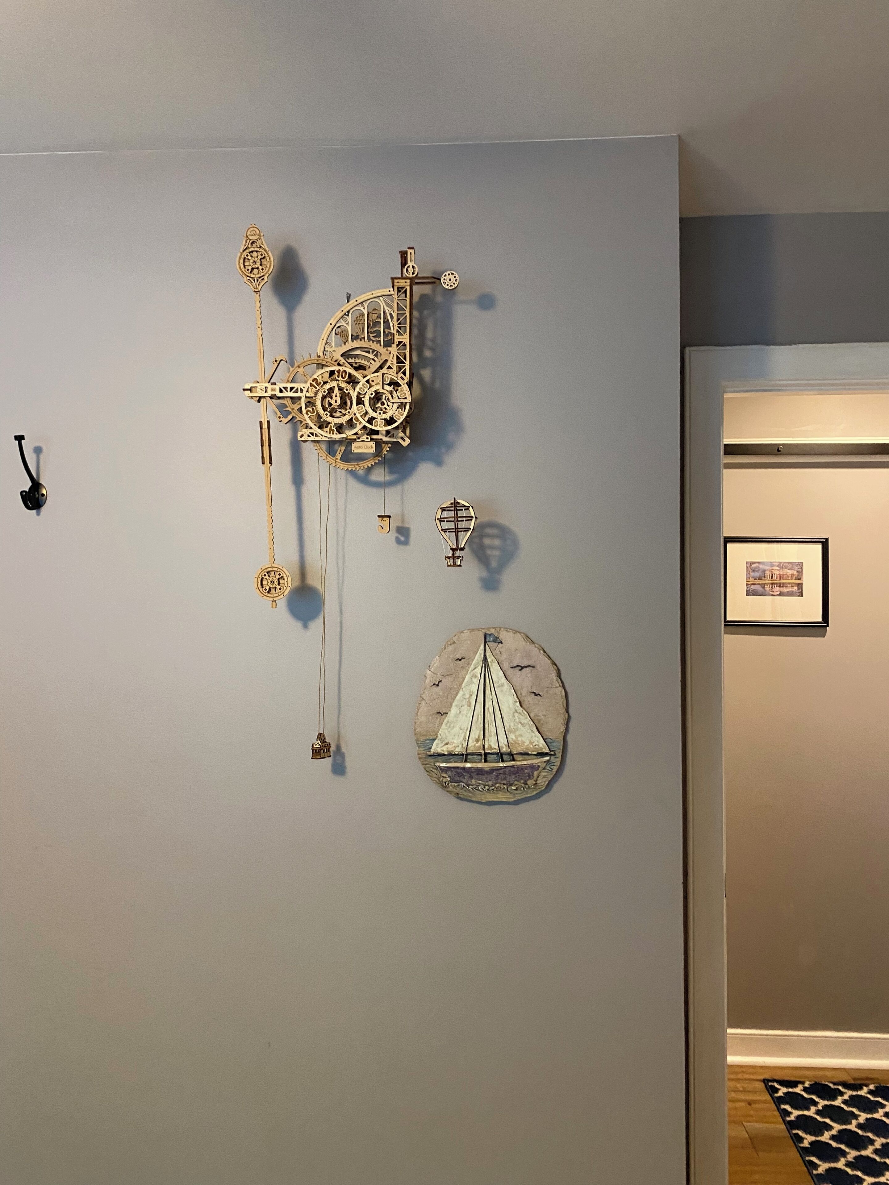 Un mur orné d’une horloge, d’une boussole, d’un navire et d’un tableau encadré.