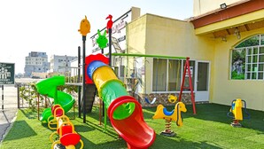 A playground with a slide, swings, and a climbing structure. - OYO 139 Al Ghadeer Hotel Apartments (Barka)