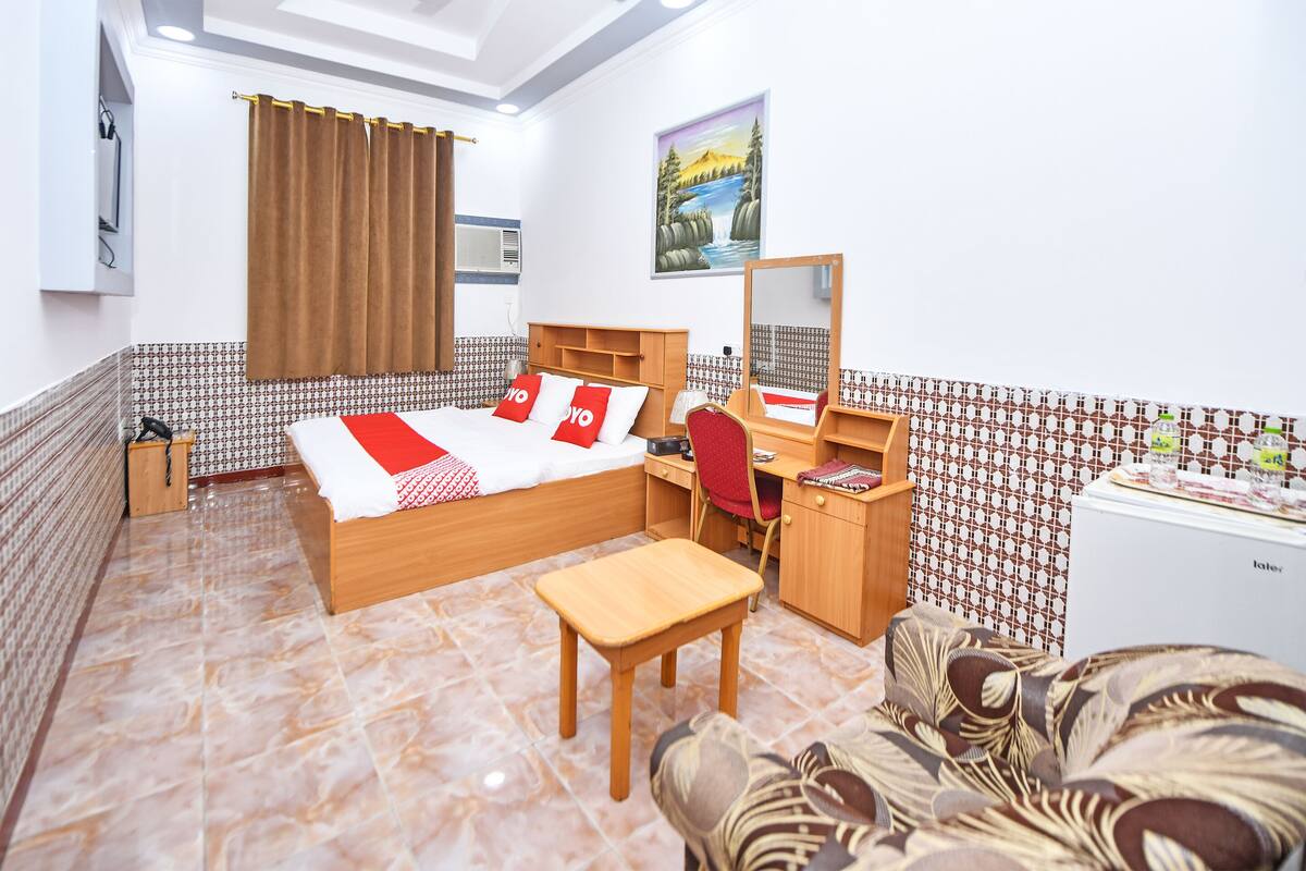 A hotel room with a bed, desk, chair, and a small table.