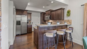 Una cocina moderna con gabinetes de madera oscura, electrodomésticos de acero inoxidable y una isla central con taburetes de bar.