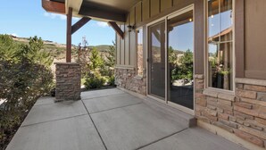 Un patio cubierto con paredes de piedra, grandes puertas correderas de vidrio y vistas a un paisaje montañoso.