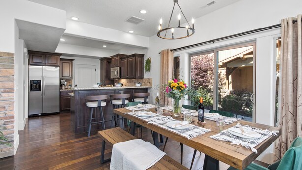 Una cocina moderna con una isla central, taburetes de bar y una mesa de comedor preparada para seis personas.