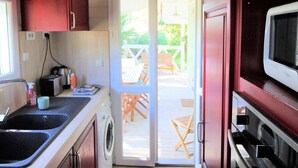 Una cocina compacta con armarios de madera, un microondas y una lavadora.