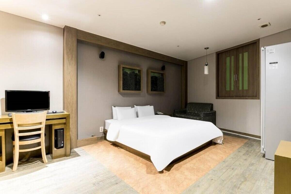 Une chambre d’hôtel moderne avec un grand lit, un bureau avec une télévision, une chaise et une armoire.