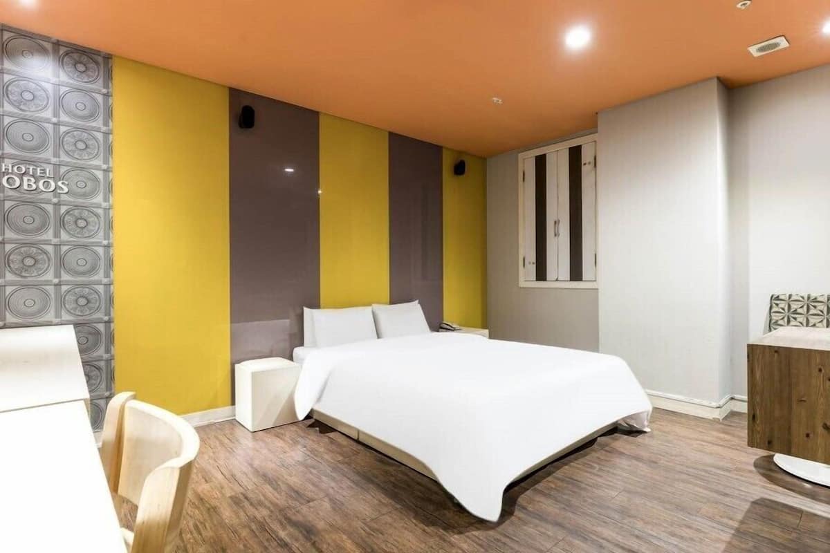 Une chambre d’hôtel moderne équipée d’un lit, d’un bureau et d’une coiffeuse.