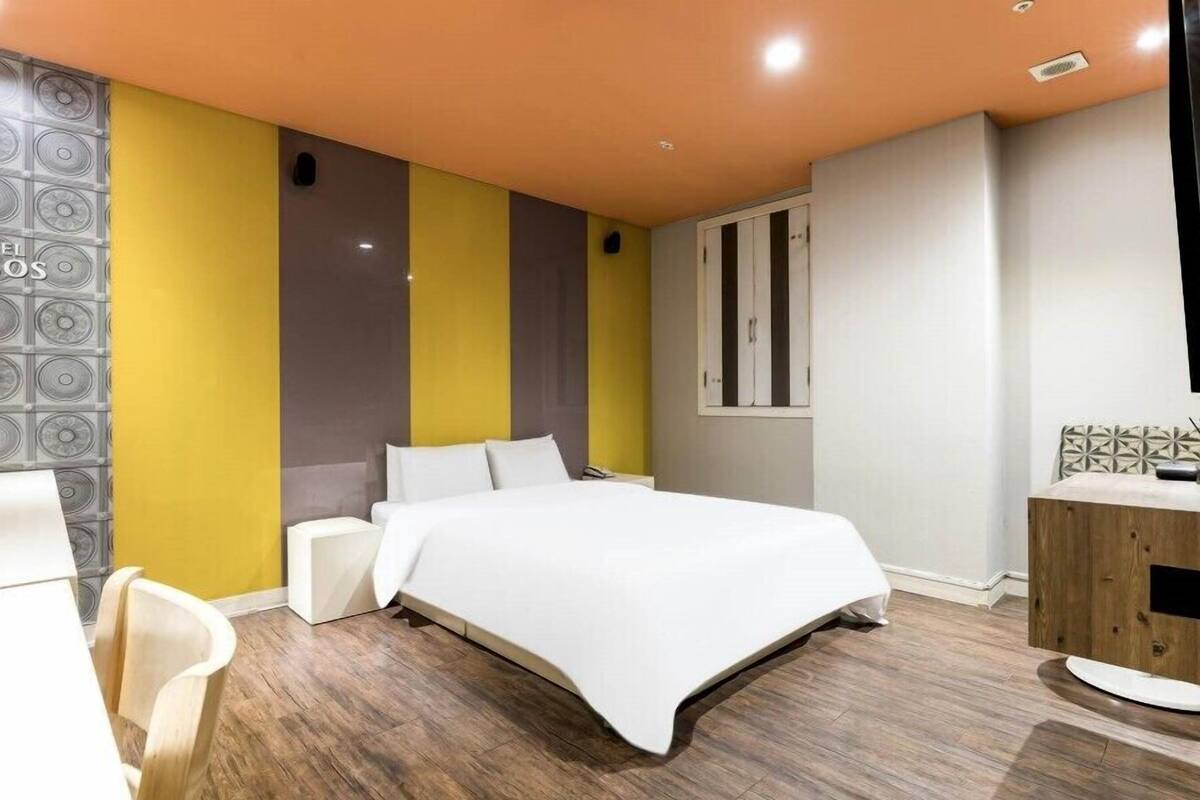 Une chambre d’hôtel moderne avec un lit, une commode en bois et un espace salle de bain.