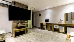 Ein modernes Wohnzimmer mit Flachbildfernseher, einer Holz-Unterhaltungseinrichtung und einem Essbereich inklusive Mikrowelle.