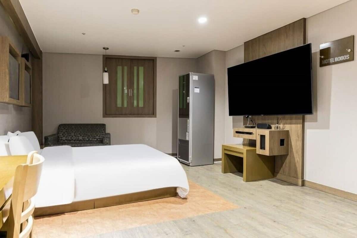 Une chambre d’hôtel équipée d’un lit, d’un bureau, d’une chaise, d’une télévision et d’un mini-bar.