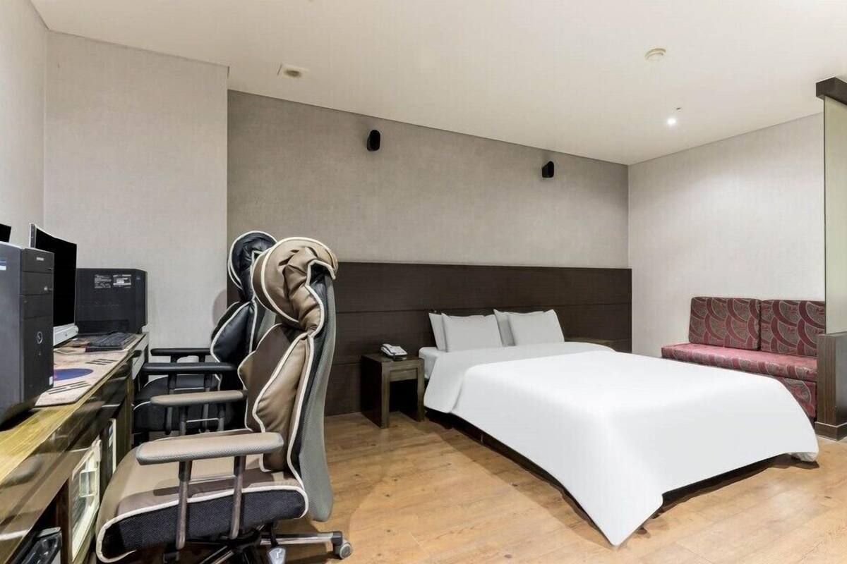 Une chambre d’hôtel avec un lit, un bureau avec un ordinateur, une chaise et un canapé.