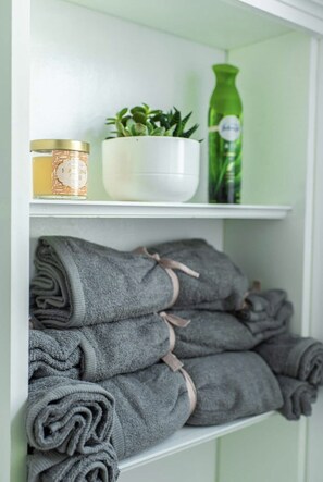 A shelf with a jar of lotion, a potted plant, and a green bottle.