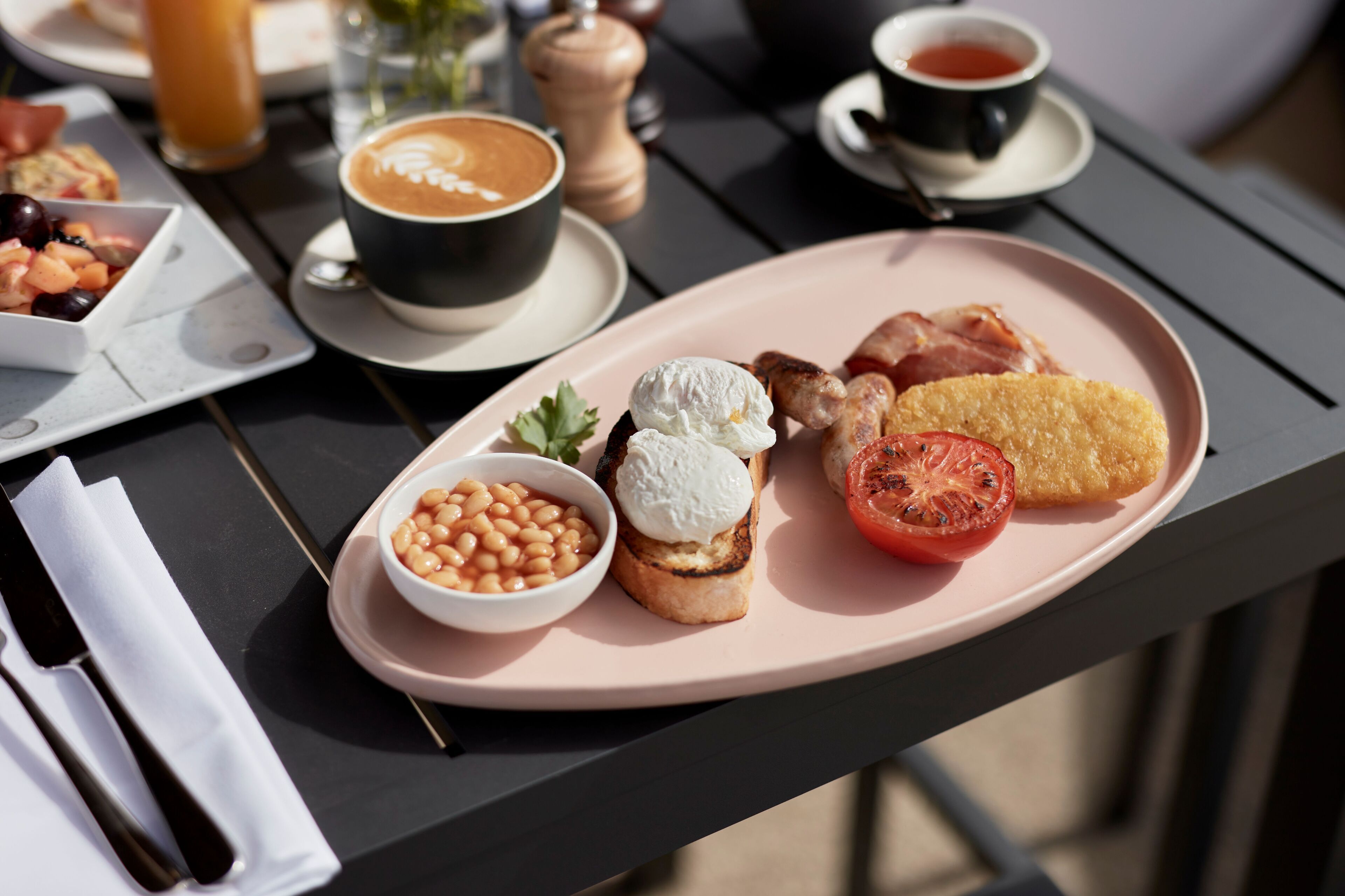 A breakfast tray with toast, beans, a tomato slice, and a poached egg on a table.