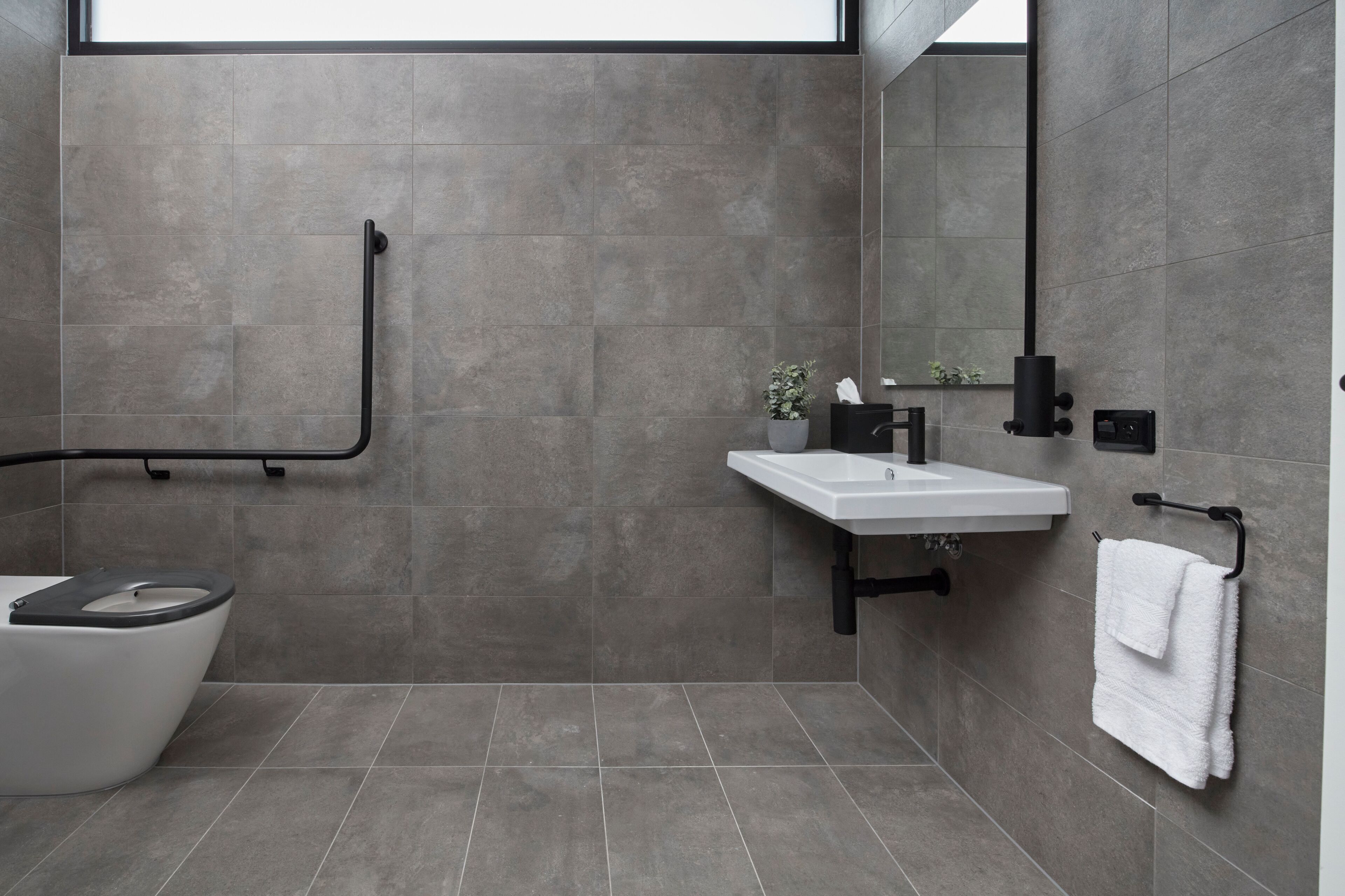 Un baño moderno con inodoro, lavamanos y toallero.