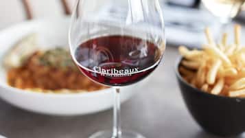 Una mesa de comedor con una copa de vino tinto, un bol de papas fritas y un plato de comida.