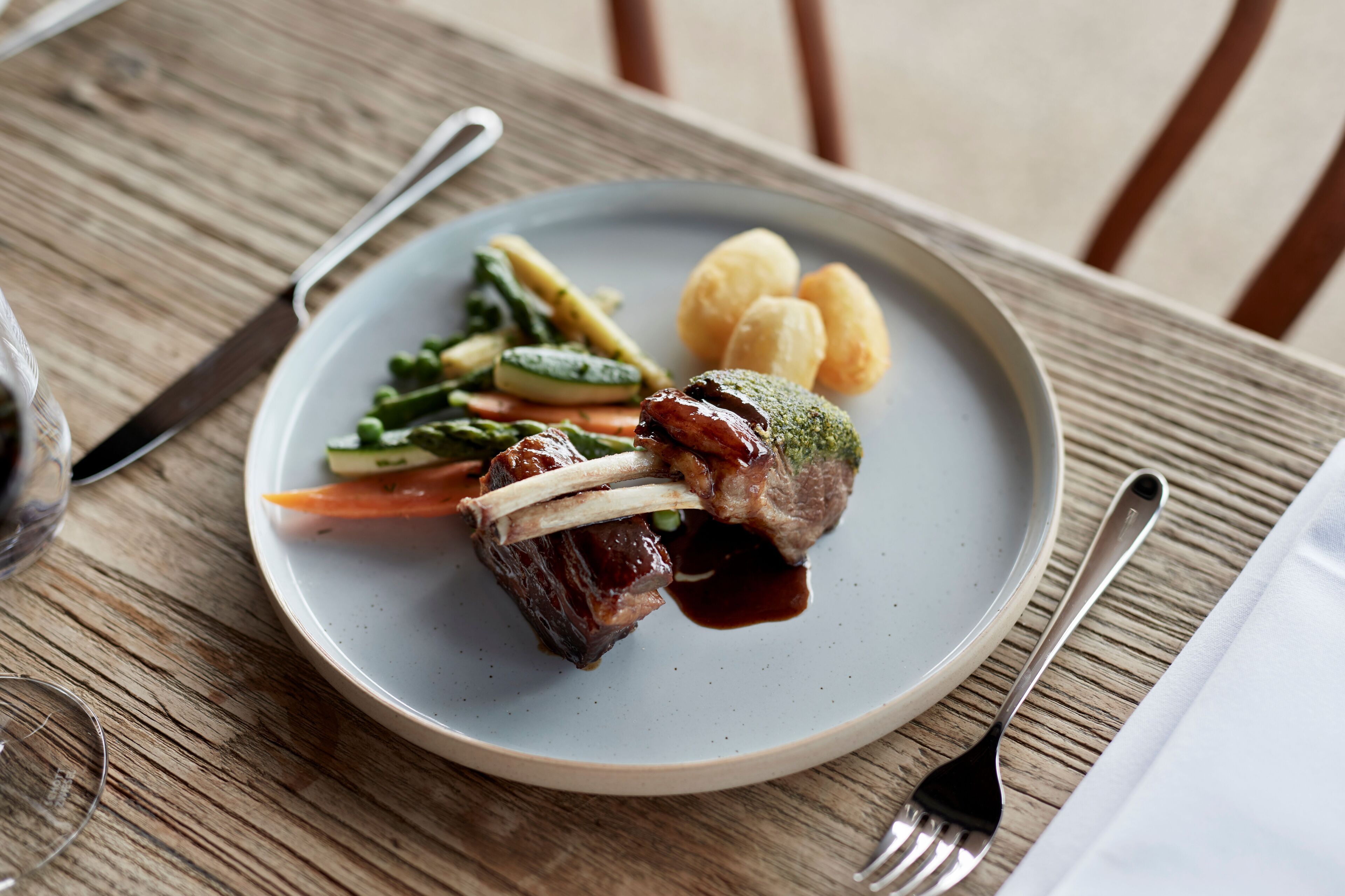 Une assiette de nourriture sur une table en bois, avec une fourchette et un couteau.