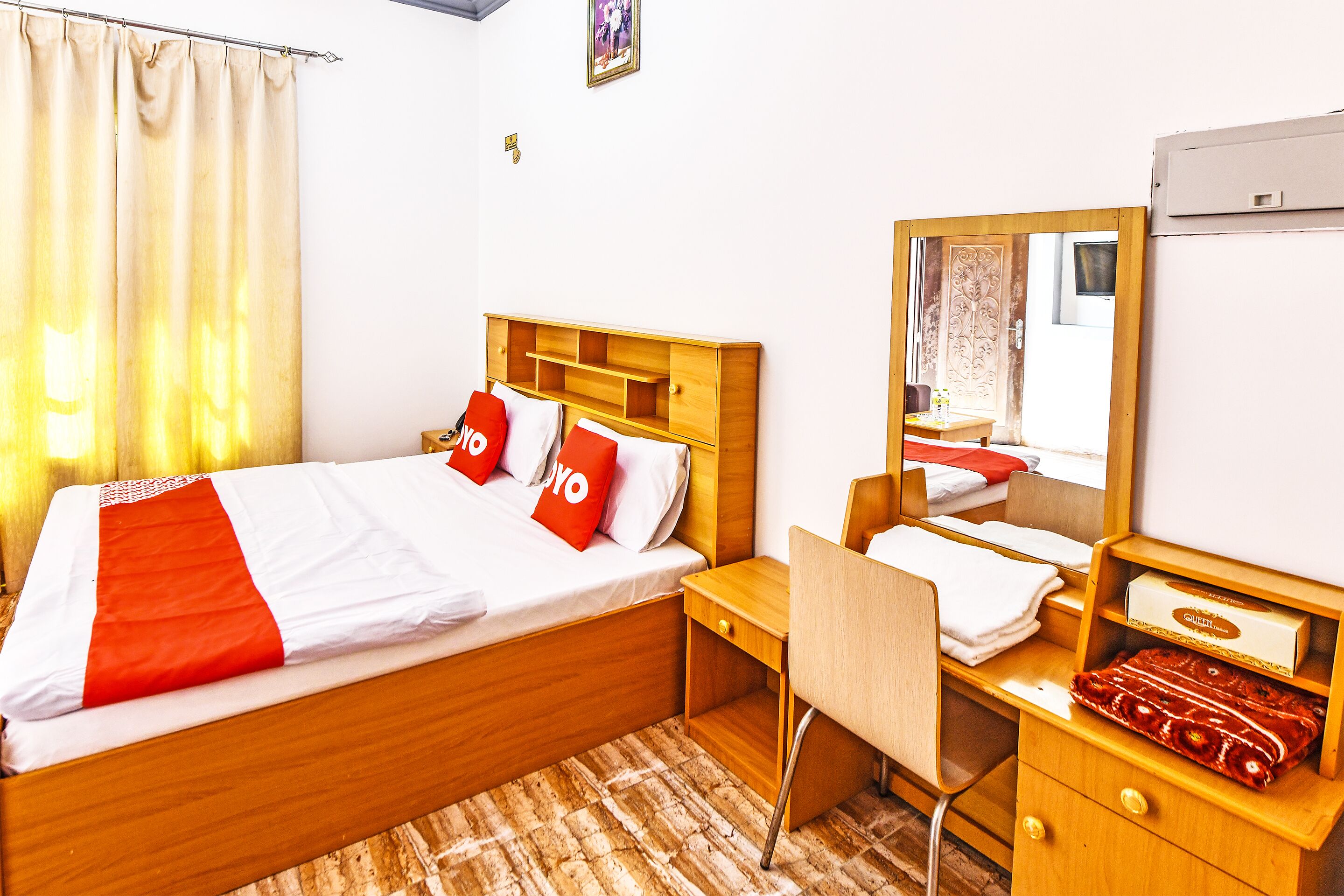 A hotel room with a bed, a desk, a chair, a mirror, and a wardrobe.