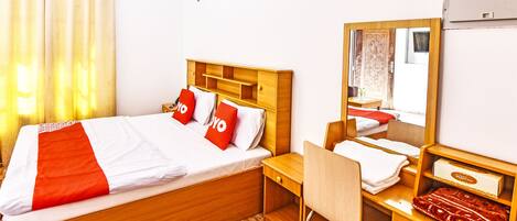 Una habitación de hotel con cama, escritorio, silla, espejo y armario.