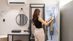A hotel room with a bed, a bedside table, a mirror, and a wall-mounted air conditioner.