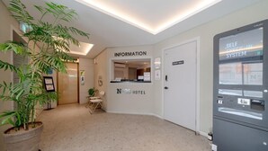 A hotel reception area with a self-check-in system, a reception desk, and a staff-only door.