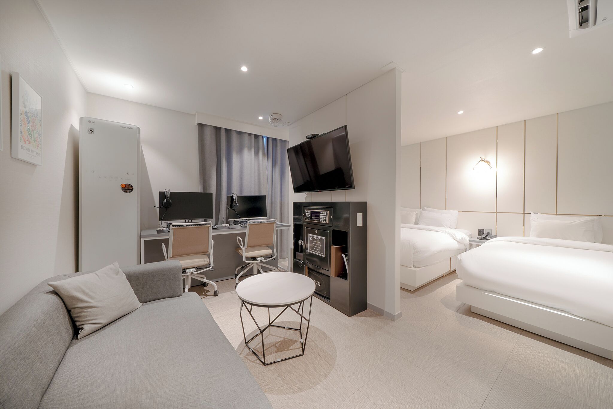 Une chambre d’hôtel moderne équipée d’un canapé, d’une petite table ronde, d’un bureau avec un ordinateur, d’une télévision et d’un lit.
