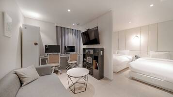 Une chambre d’hôtel moderne équipée d’un canapé, d’une petite table ronde, d’un bureau avec un ordinateur, d’une télévision et d’un lit.