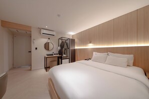 Una habitació d'hotel moderna amb un llit gran, panells de fusta a les parets, un escriptori amb una cadira i un armari.
