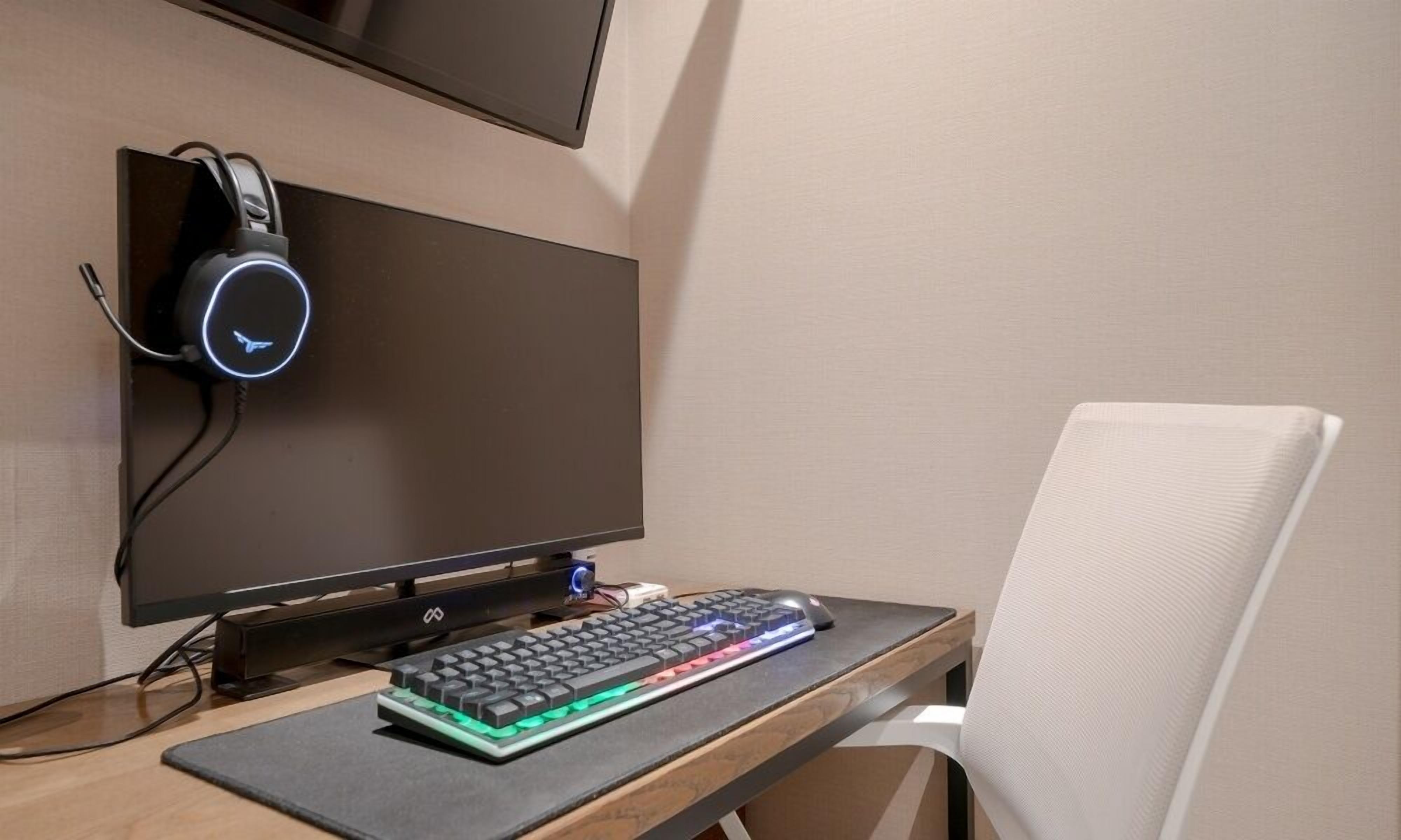 A computer setup with a monitor, keyboard, headphones, and a mouse on a desk.
