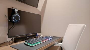 A computer setup with a monitor, keyboard, headphones, and a mouse on a desk.