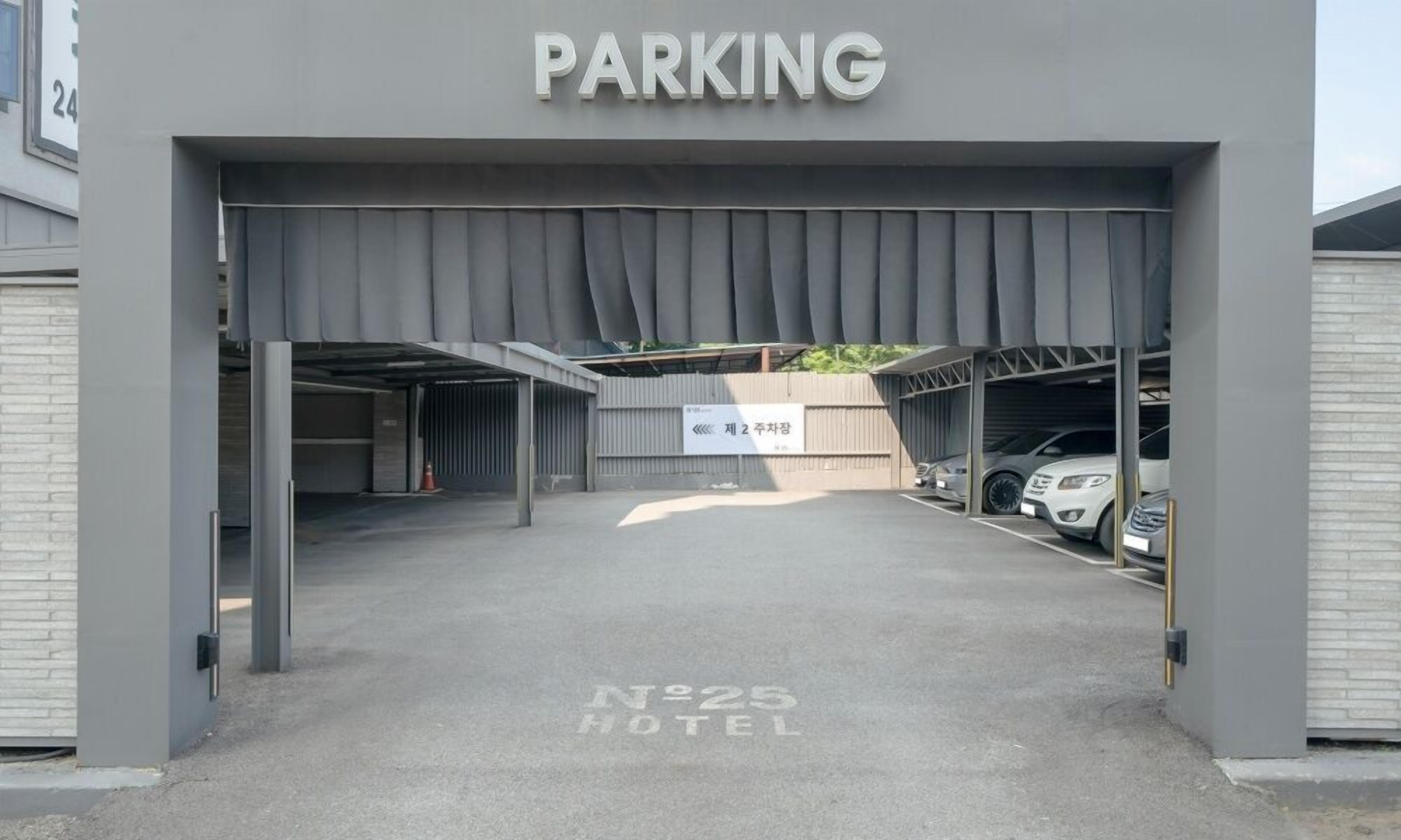 Entrada de estacionamiento a un hotel, con un letrero que indica 'PARKING' y otro con la indicación 'No. 25 HOTEL'.