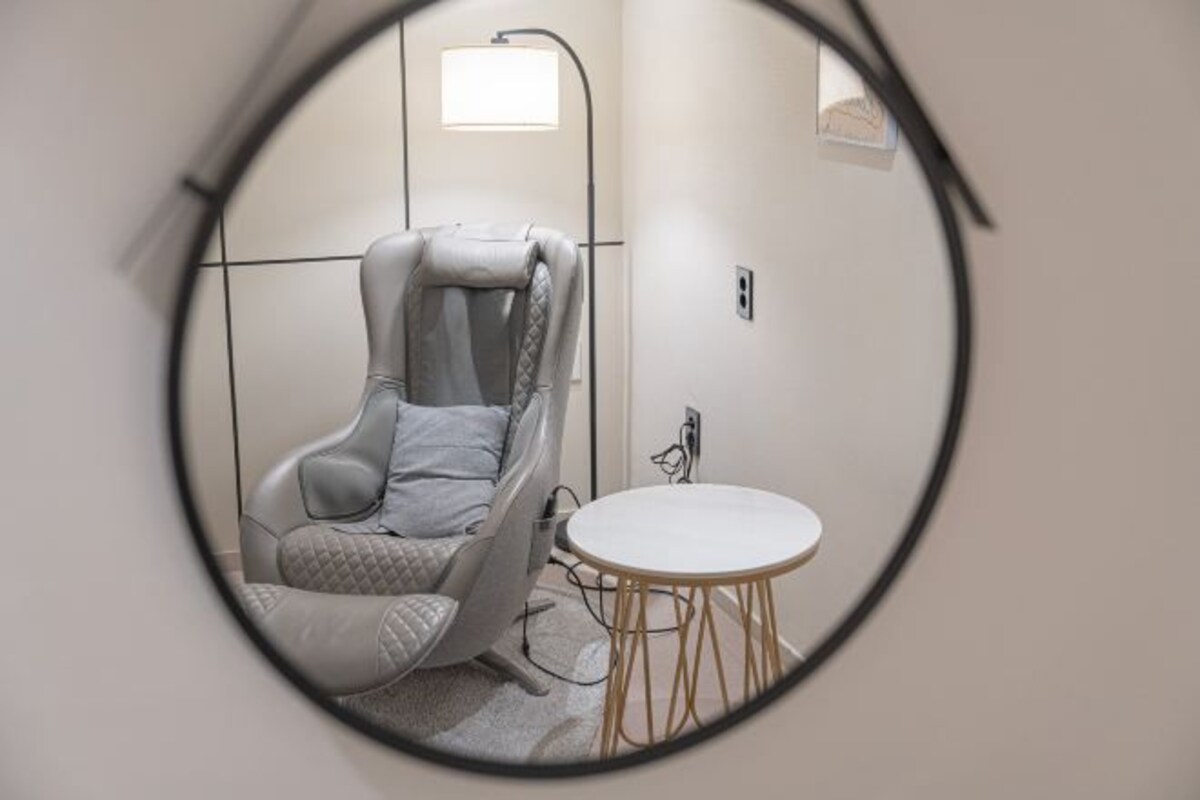 Habitación moderna con un espejo circular único que refleja una silla y una mesita.