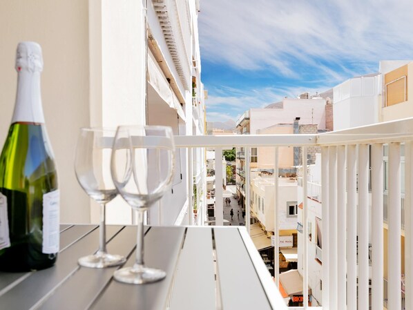A balcony with a bottle of wine and two glasses, overlooking a cityscape with buildings and a clear sky. - Conypra Modern and Renovated with Terrace (Arona)