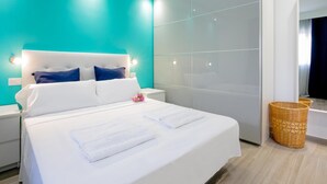Une chambre d’hôtel moderne avec un grand lit, un mur d’accent de couleur turquoise et un grand miroir.