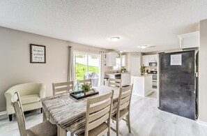 Una cucina moderna con zona pranzo, che include un tavolo con sedie, un frigorifero e vista sull'esterno.