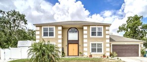 A two-story house with a brown front door, a garage, and a well sign. - Spacious Estate Home with large Pool and Jacuzzi, Near Beaches, Springs & Tampa (Spring Hill)