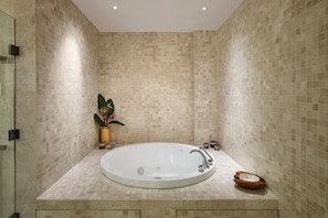 Une salle de bain moderne avec une grande baignoire, un petit lavabo et une plante en pot.