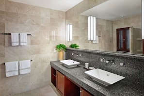 Features a large mirror, granite countertop, and two sinks under wooden cabinets.