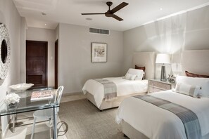Relax in a serene space with a glass dining table, two single beds, and a ceiling fan.