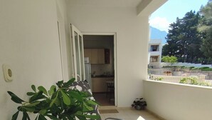 A balcony with a round table, a potted plant, and a view of the kitchen and mountains in the background. - Spacious studio apartment with a  terrace,parking,free WiFi and AC in Baška Voda (Baška Voda)