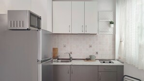 A modern kitchen with a refrigerator, microwave, sink, and a dining area with a table and chairs. - Spacious studio apartment with a  terrace,parking,free WiFi and AC in Baška Voda (Baška Voda)