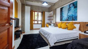 Una habitación de hotel moderna con una cama grande, un escritorio con una silla, un televisor y un cuadro abstracto de gran tamaño en la pared.