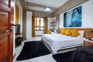 Una habitación de hotel moderna con una cama grande, un escritorio con una silla, un televisor y un cuadro abstracto de gran tamaño en la pared.