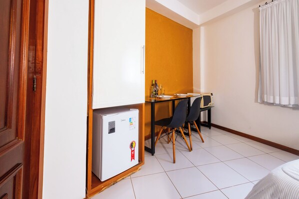 Una habitación compacta con kitchenette, una mesa de comedor con sillas y una cama.
