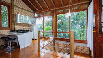 Una cocina con techo de madera, pared de ladrillo y un amplio ventanal con vistas a follaje.