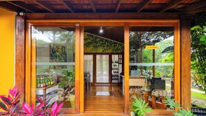 Una estructura de madera con puertas de vidrio que dan a una sala con piso de baldosas y una zona de recepción con un cartel.