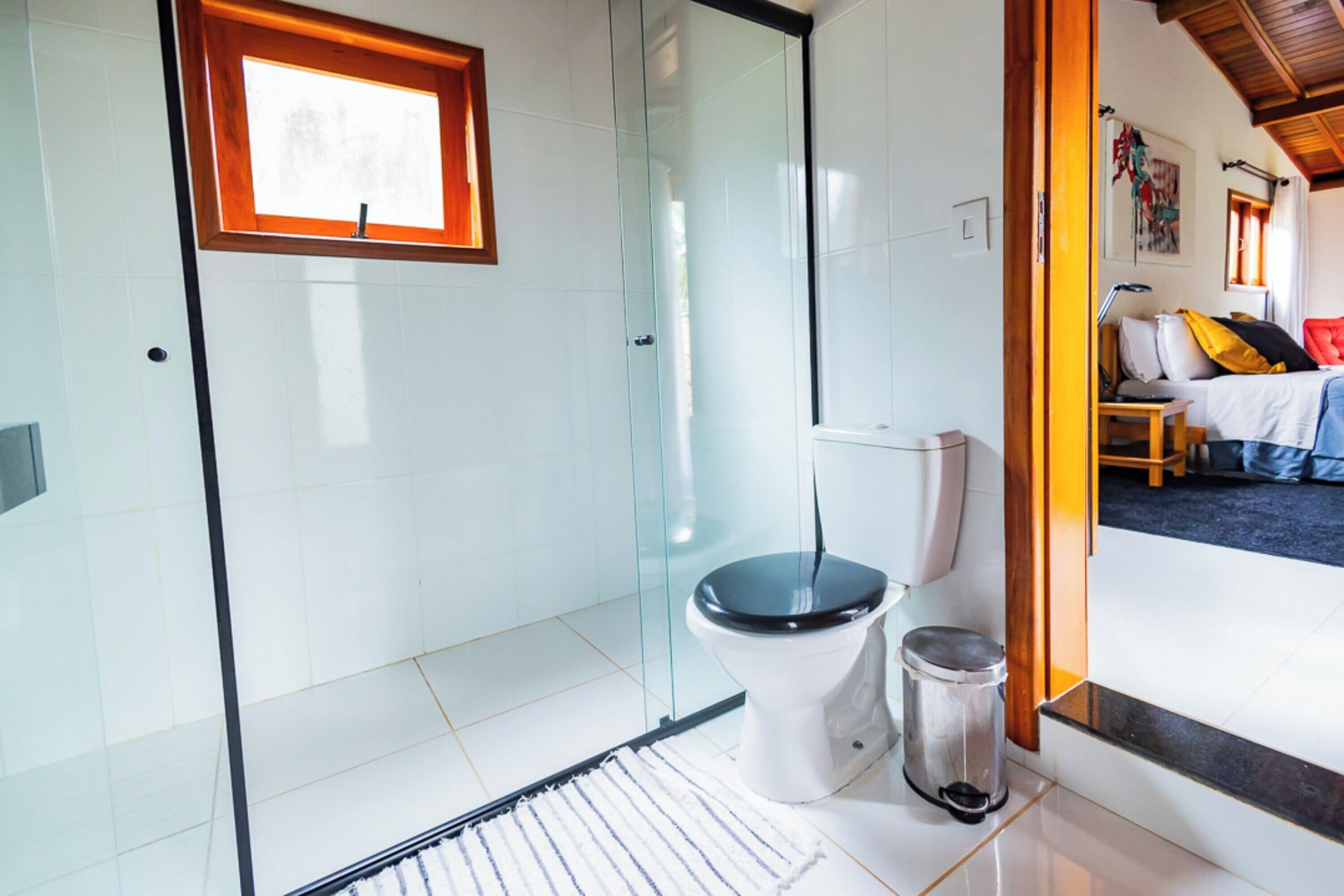 Un baño moderno con cabina de ducha de vidrio, inodoro blanco y un cubo de basura.