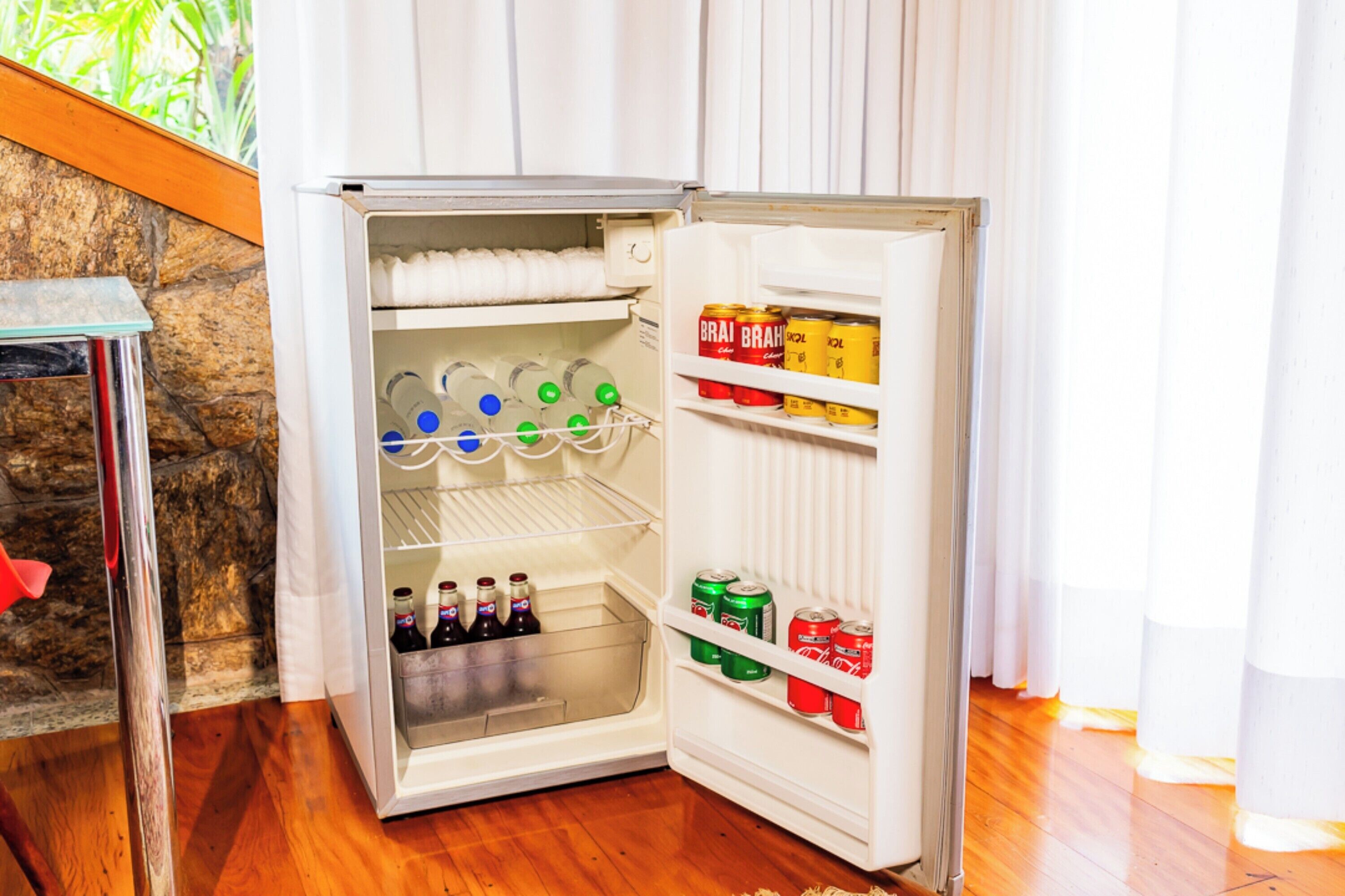 A small refrigerator with shelves containing beverages and cans.
