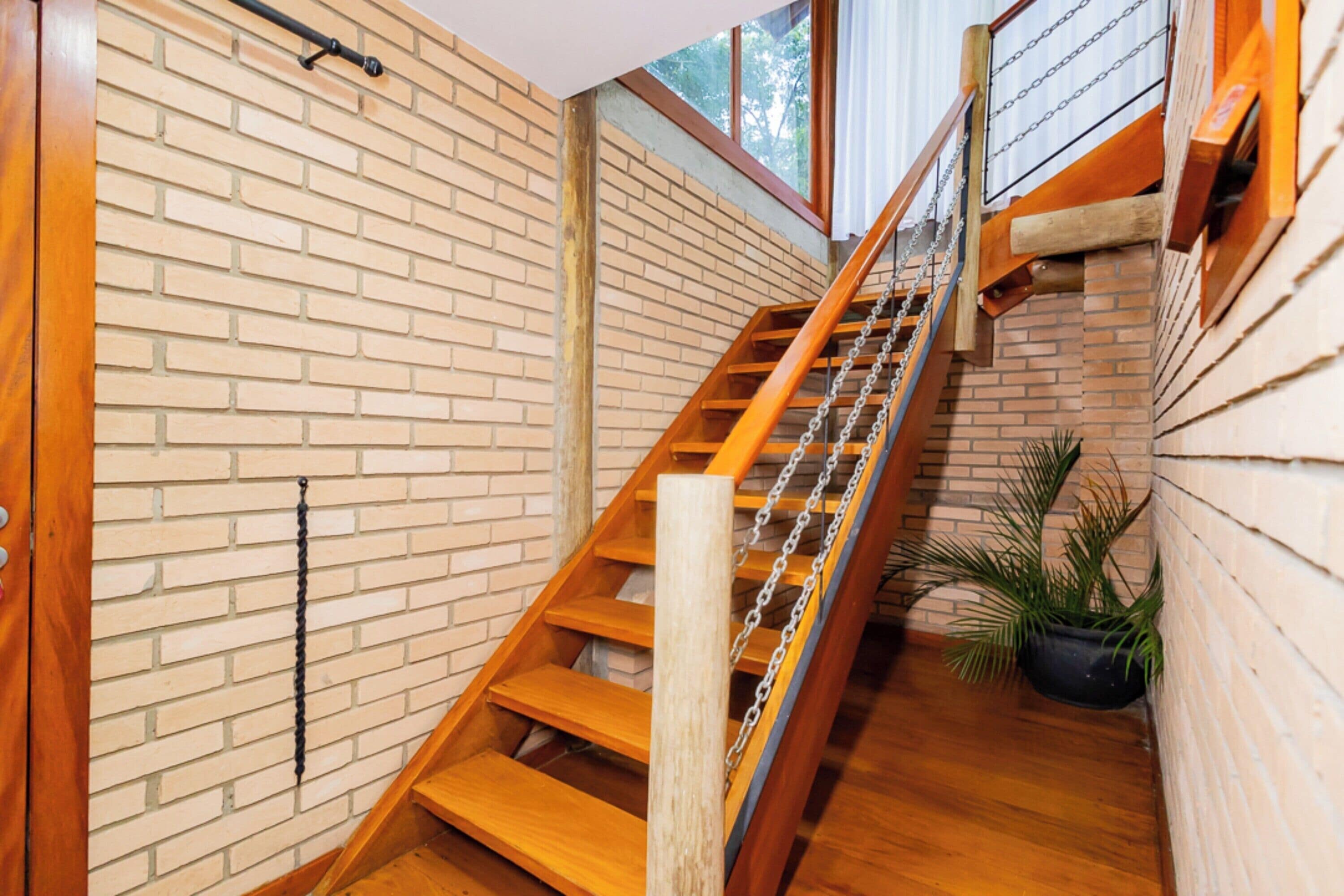 A wooden staircase with a brick wall on one side and a window on the other.