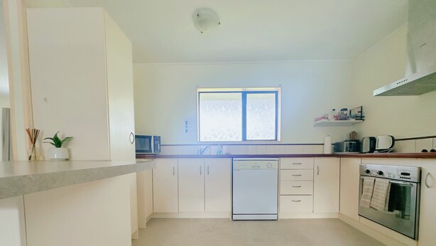 A modern kitchen with white cabinets, a dishwasher, a microwave, and an oven. - Perfect for Large group-Near Redwood Forest (Rotorua)