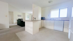 A modern kitchen with white cabinets, a microwave, and a dishwasher. There is a large window providing natural light. - Perfect for Large group-Near Redwood Forest (Rotorua)