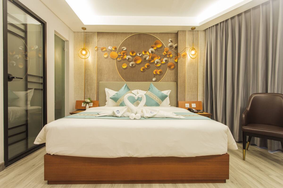 Ein modernes Hotelzimmer mit einem großen Bett, einem Wandbild und einer Sitzecke.