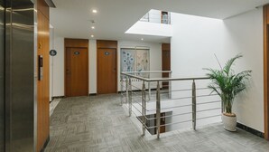 A modern hotel lobby with a staircase, wooden doors, and a potted plant. - Thapae Twins Hotel (Chiang Mai)